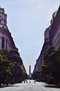 Road amidst buildings in city against sky
