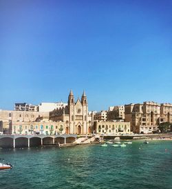 View of buildings at waterfront against blue sky