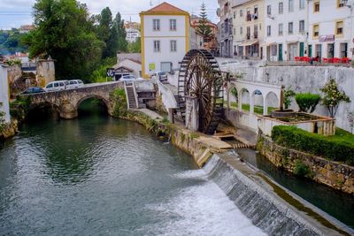 Arch bridge over river amidst buildings in city