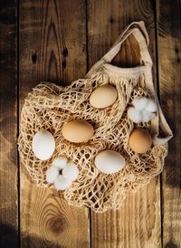 Easter concept. beige mesh shopping bag with brown chicken eggs on a wooden background.