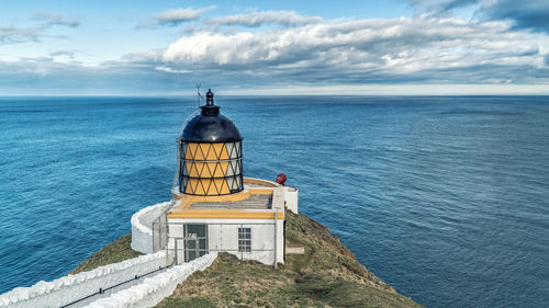 Lighthouse by sea against sky