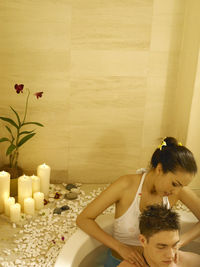 Girlfriend giving massage to boyfriend in bathtub