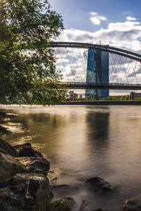 Bridge over river against cloudy sky