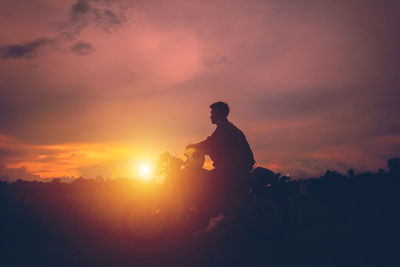 Silhouette man riding motorcycle against sky during sunset