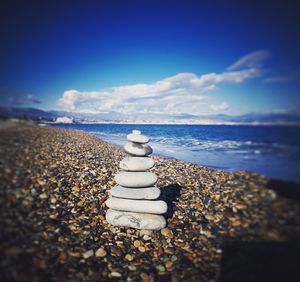 Stack of pebbles on beach against sky