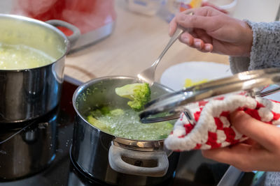 Woman cooking on cooker in the kitchen with hot steam and pots on a ceran stove to cook