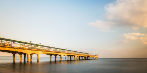 Bridge over sea against sky during sunset