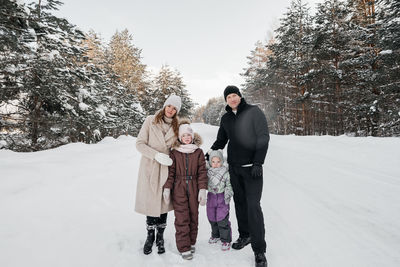 Dad and mom and two daughters walk through the snowy forest. high quality photo