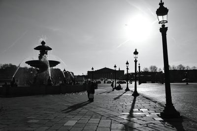 People at fountain on sidewalk against sky