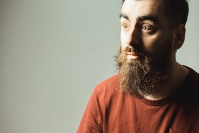 Young man looking away against standing against gray background