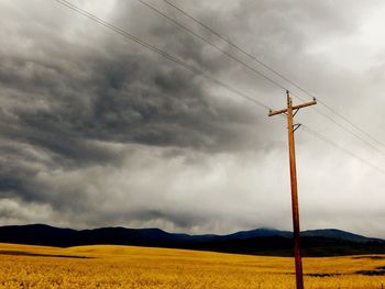 Electricity pylon on field against sky