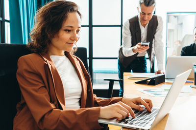 Portrait of young woman using laptop at office