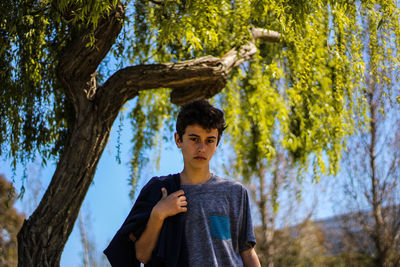 Boy standing by tree