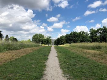 Trail amidst trees on field against sky