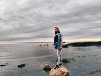 Woman standing at beach against sky