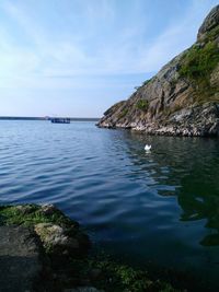 Scenic view of sea by cliff against sky