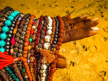 Cropped hand of man selling bead necklaces at beach