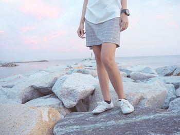 Low section of woman standing on beach against sky