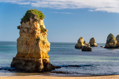 Rock formation on beach against sky