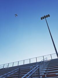 Low angle view of stadium against airplane flying in clear blue sky