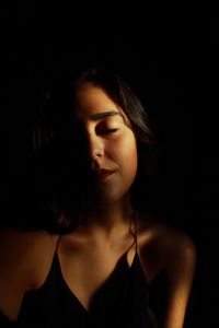 Close-up portrait of young woman over black background