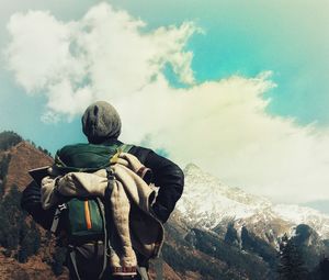 Rear view of male hiker looking at mountain against cloudy sky