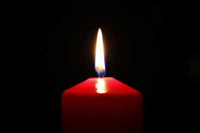 Close-up of lit candle in darkroom