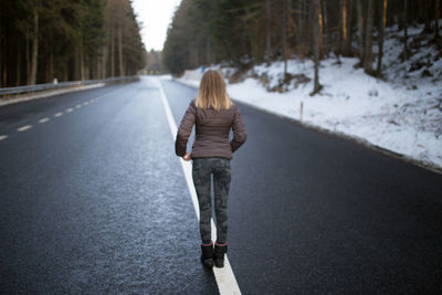 Rear view of woman walking on road in winter