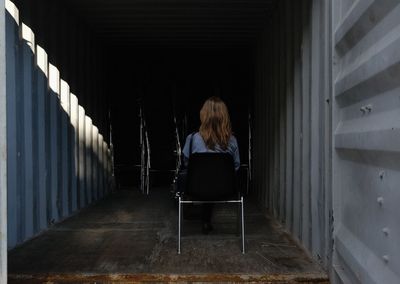 Rear view of woman sitting in corridor