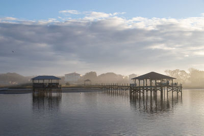 Wooden pier with boat lifts on a river in the morning fog