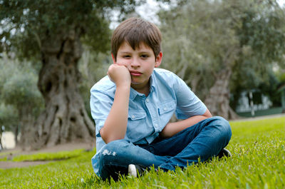 Portrait of boy sitting on field