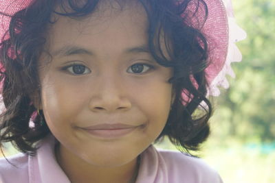 Close up portrait curly hair little girl with hat smiling to camera