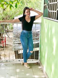 Portrait of smiling young woman standing against wall