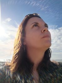 Close-up of thoughtful mid adult woman looking away against sky