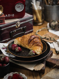 Fresh baked croissant with strawberry fruits in ceramic black plate