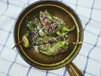 Fried padron peppers with sea salt flakes in rustic, green ceramic dish