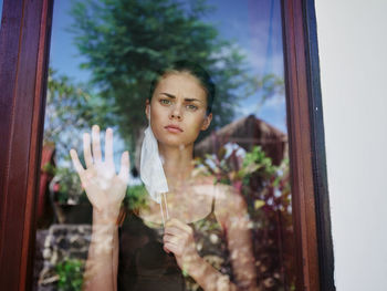 Portrait of young woman looking through window