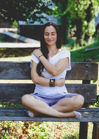 Young woman sitting on bench in park