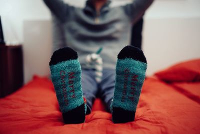 Low section of man wearing socks on bed