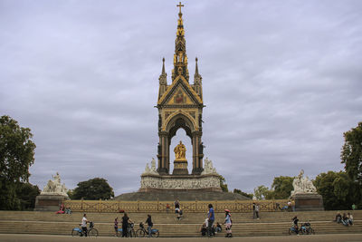 People at historical building against cloudy sky