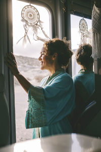 Rear view of woman looking through window