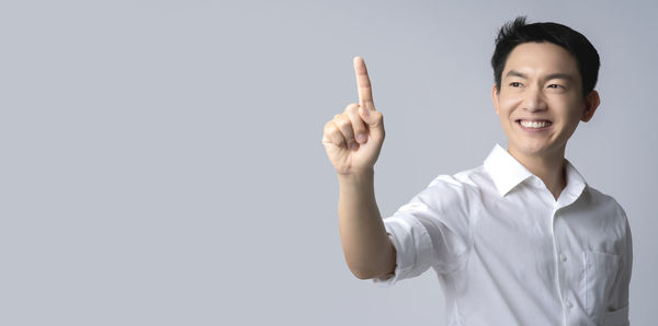 Portrait of young man standing against white background