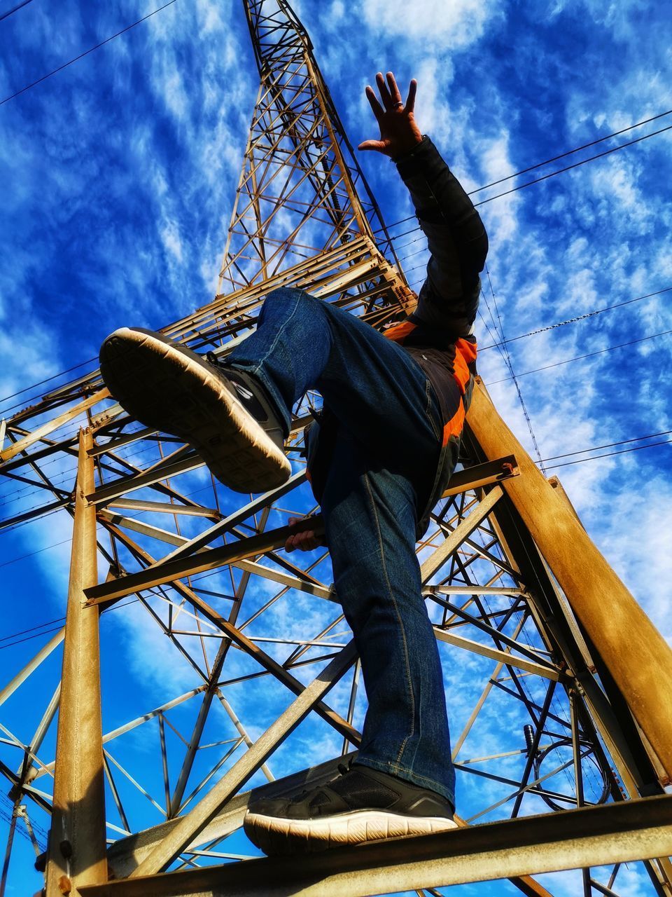 LOW ANGLE VIEW OF MAN CLIMBING AGAINST SKY