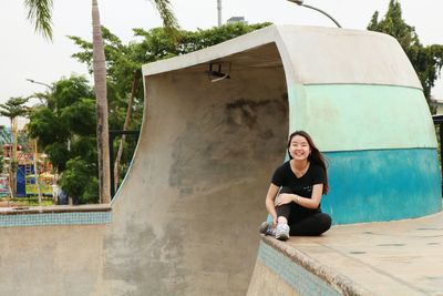 Young woman sitting against wall