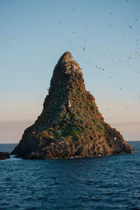 Rock formation in sea against sky