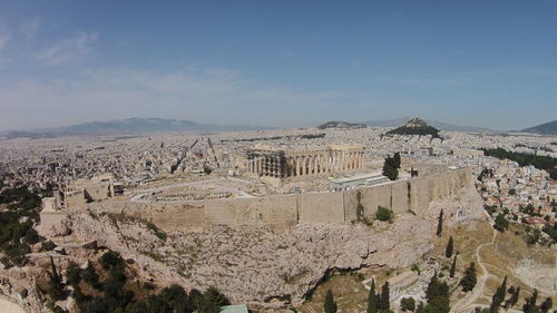 Parthenon on acropolis by residential district against sky