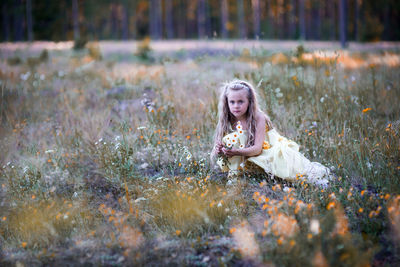 Portrait of cute girl collecting flowers from field