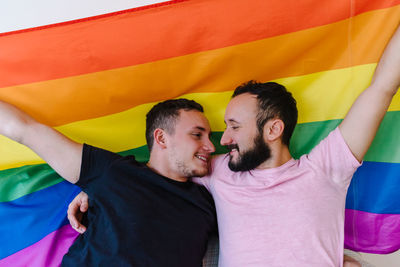 Two homosexual men holding lgbtq flag.