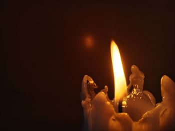 Close-up of burning candle against black background