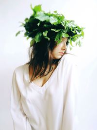 Close-up of woman with flowers against white background